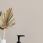 Bathroom Storage - Set of cosmetic supplies near decorative leaves in vase on marble shelf