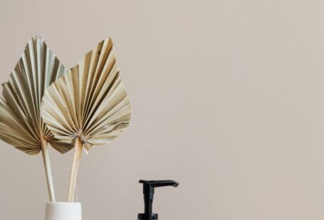 Bathroom Storage - Set of cosmetic supplies near decorative leaves in vase on marble shelf