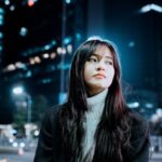 Outdoor Lighting - Brunette Girl Sitting on Bench in City Street at Night