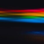 Lighting Trends - Colorful abstract background with blurred glowing rainbow lights in modern dark studio with black wall and creative bright optical effect