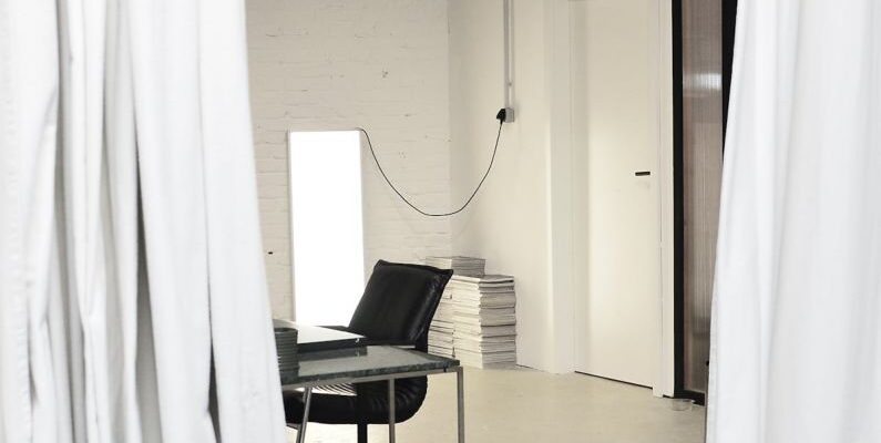 Loft Apartment - Interior of spacious loft studio with meeting table and chairs surrounded by hanging white curtains